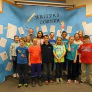 Students posing in front of a bulletin board at a school event.