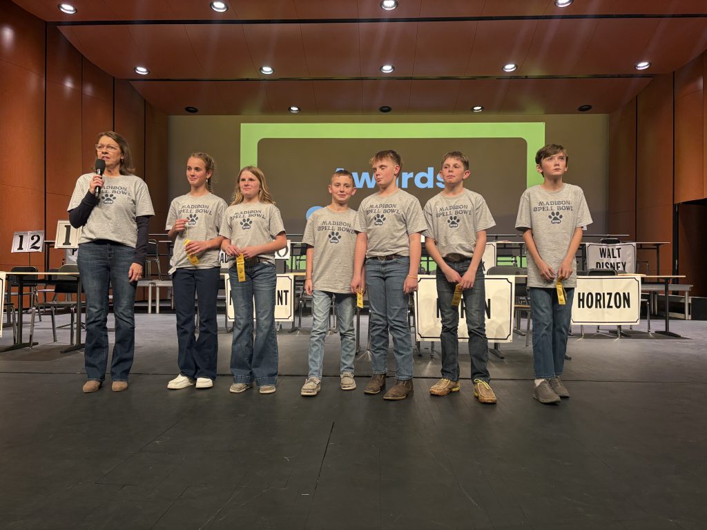 A group of young people standing on stage at a competition, posing for a picture.
