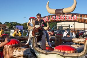 Boy riding mechanical bull ride at PHM Homecoming Fun Zone